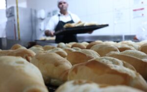 Panadero con una bandeja de masa en el obrador de una panadería
