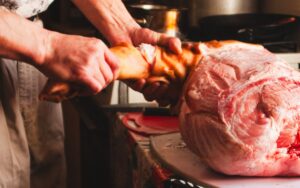 Profesional de carnicería cortando carne en el mostrador de un supermercado